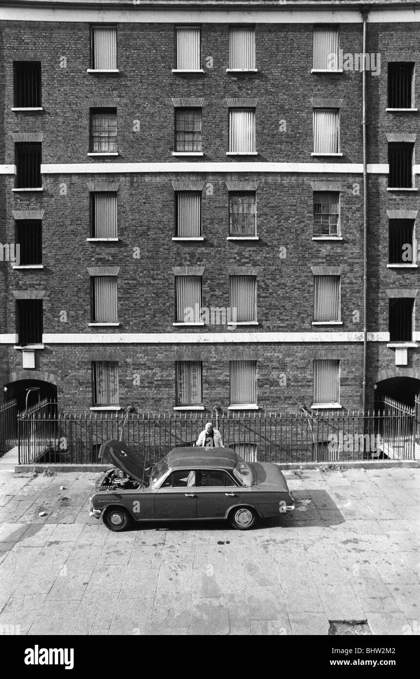 Tenement Victorian slums Peabody Housing Estate. Tower Hamlets Whitechapel east London UK 1970s. Man working on his car in front of his housing block. 1978 HOMER SYKES Stock Photo