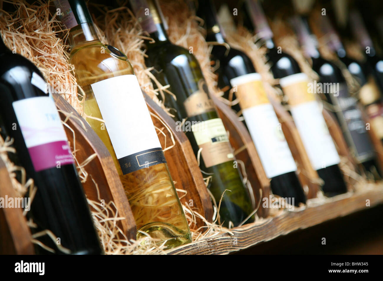 Closeup shot of wineshelf. Bottles lay over straw. Stock Photo