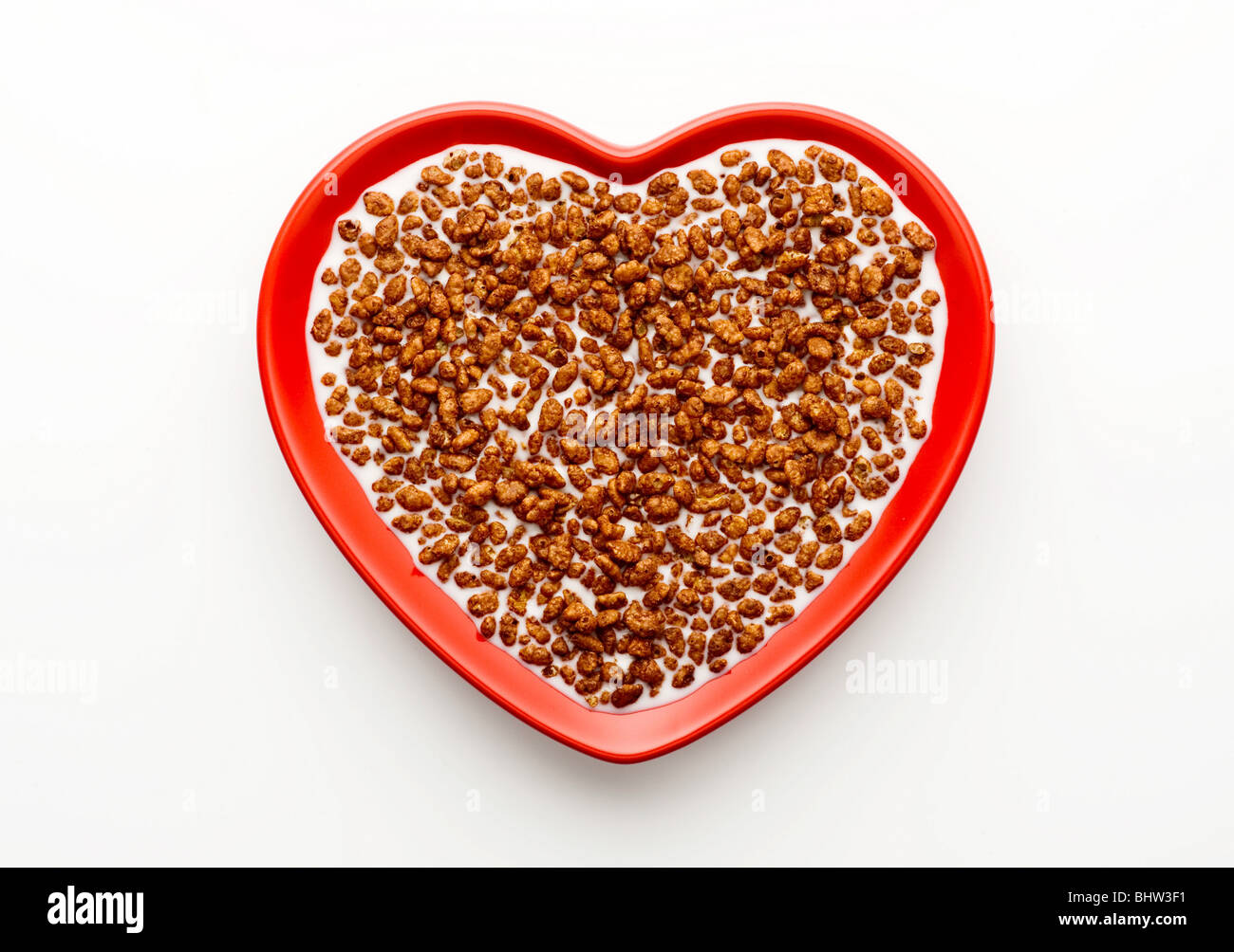 Studio shot of red heart shaped bowl of coco pops and milk on a white