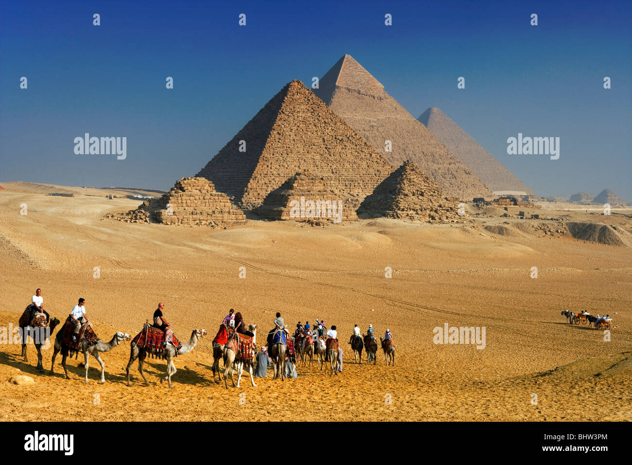 Tourists riding camels at the Pyramids of Giza, Cairo, Egypt Stock