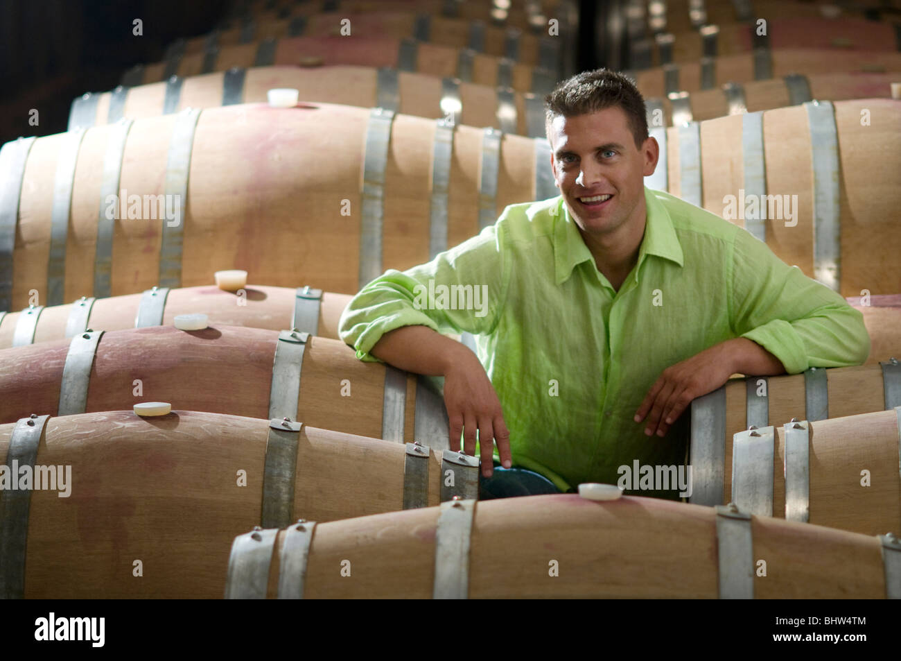 Young man in wine cellar with wooden barrels Stock Photo - Alamy