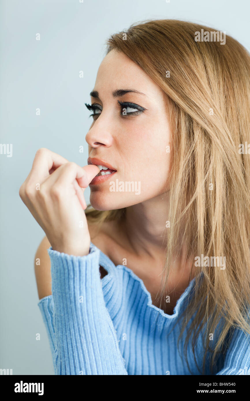 portrait of 30 years old woman biting her fingernails on cyan background. Vertical shape Stock Photo