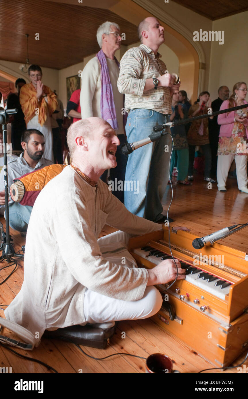 Hare Krishna devotee singing and playing a harmonium at a Sunday afternoon Kirtana (Chanting ceremony) Stock Photo