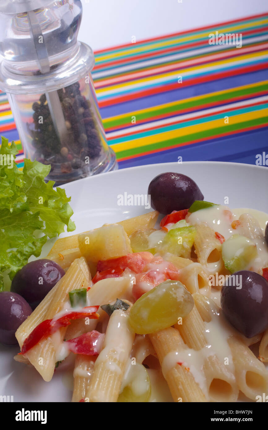 Cooked pasta dish alongside a pepper mill. Stock Photo