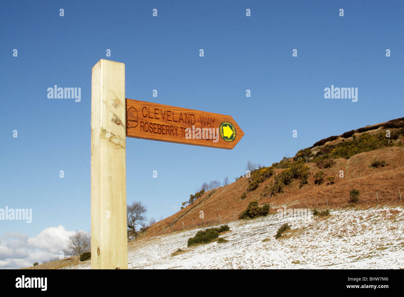 Wooden public bridleway sign pointing to Roseberry Topping on the Cleveland Way long distance walk with snow in foreground Stock Photo