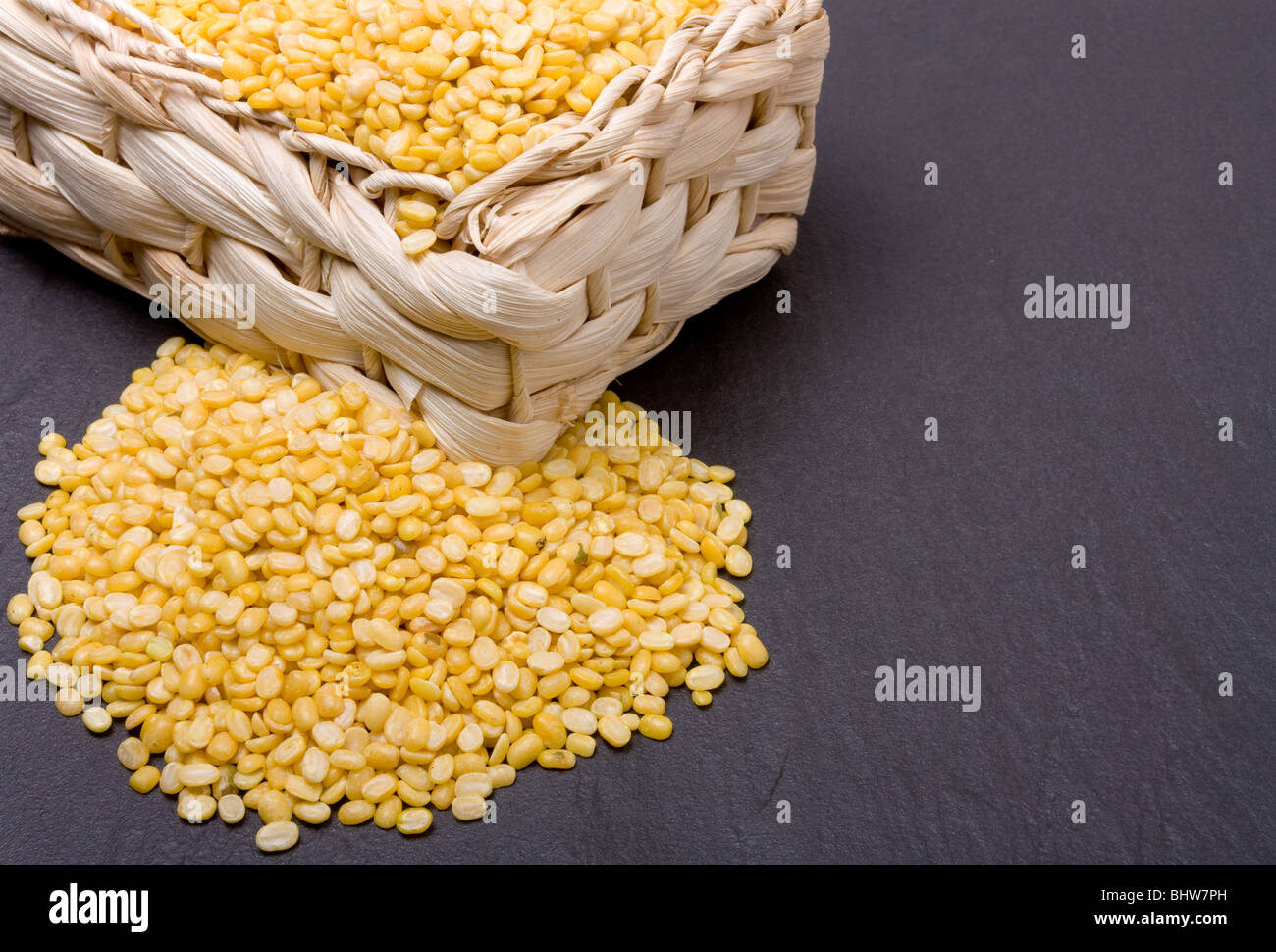 Vibrant yellow Moong Daal lentils or mung bean lentils against dark slate. Stock Photo