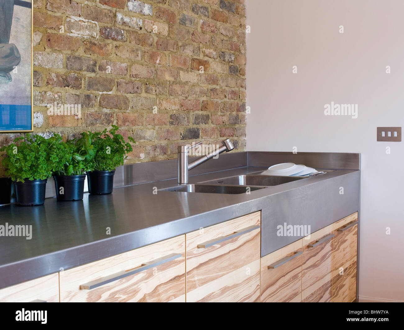 Exposed Brick Wall Above Stainless Steel Worktop On Wood Veneer