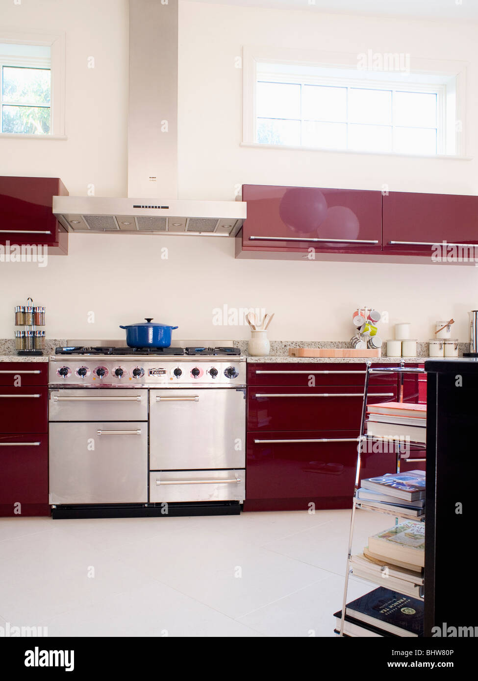 Stainless steel range oven in modern kitchen with white flooring and dark red wall-cupboards Stock Photo