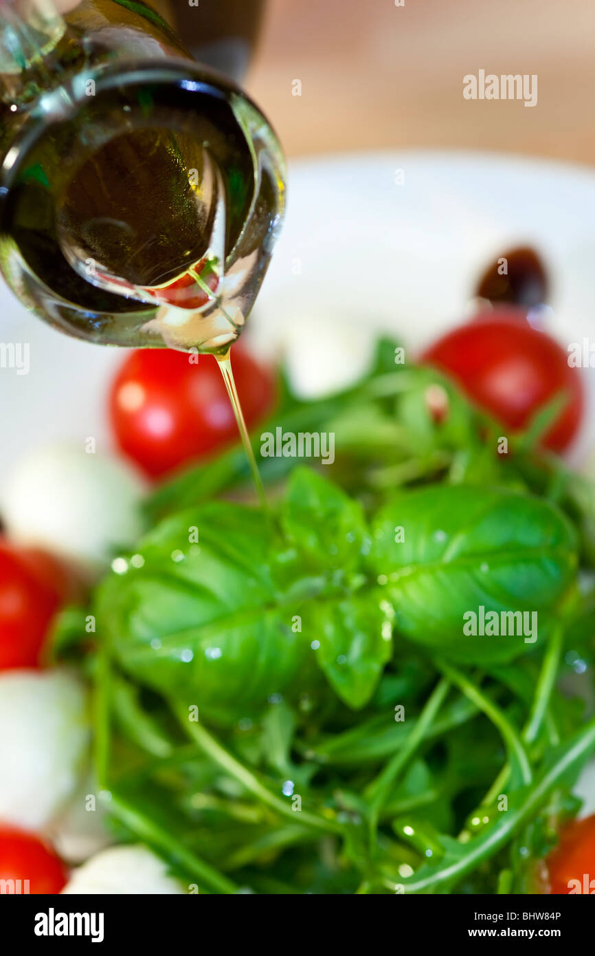 Close up macro photograph of olive oil dressing being poured onto fresh