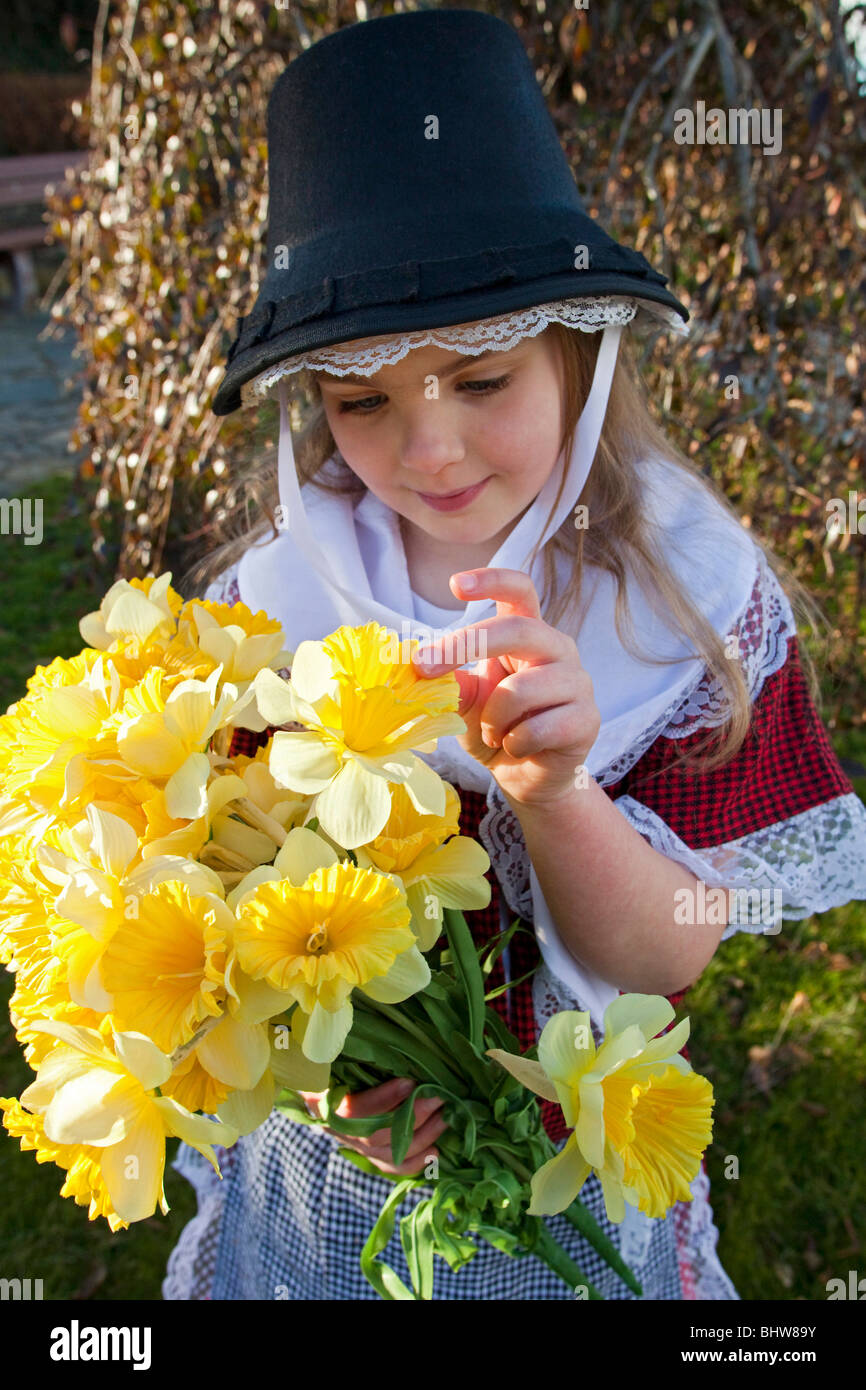 Young girl with bunch of yellow daffodils wearing traditional welsh