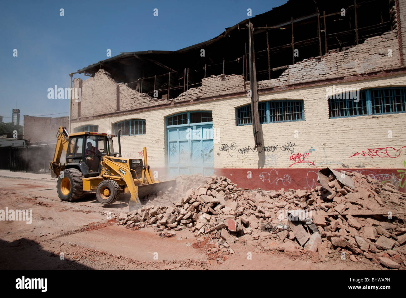 A Bucket Loader cleaning the debris of a collapsed wall Stock Photo - Alamy