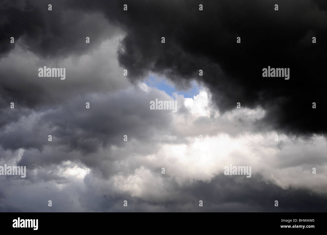 A patch of blue sky shows through black and grey thunder clouds
