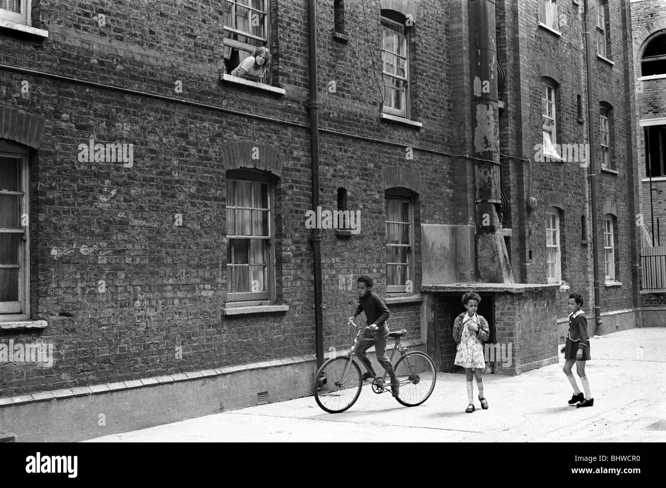 Victorian Slum Building Peabody Housing Estate. Tower Hamlets Whitechapel east London UK 1970s. Multiracial Britain, immigrant children playing in the communal area of the block of flats. 1975  HOMER SYKES Stock Photo