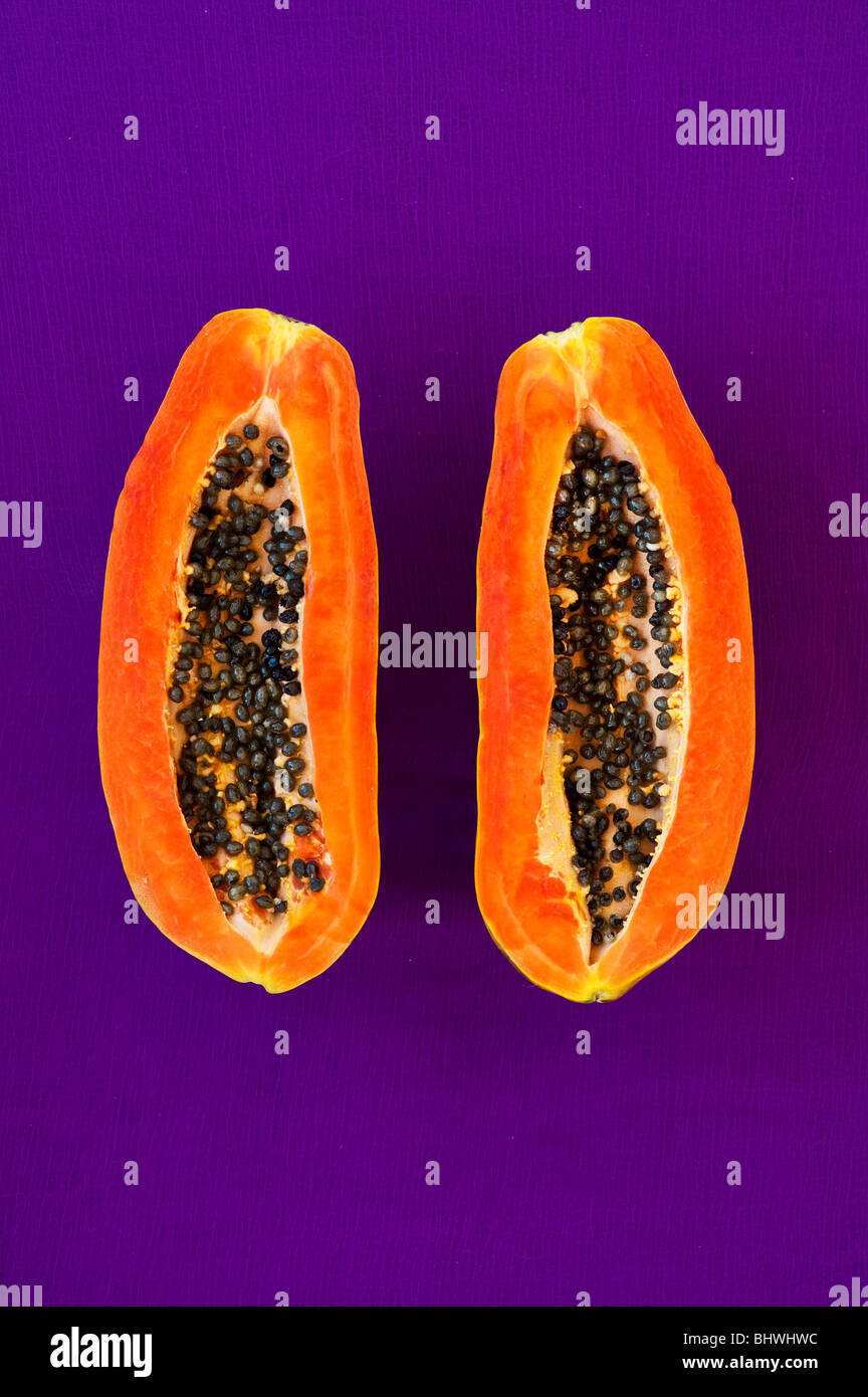 Cut papaya with seeds against purple background Stock Photo