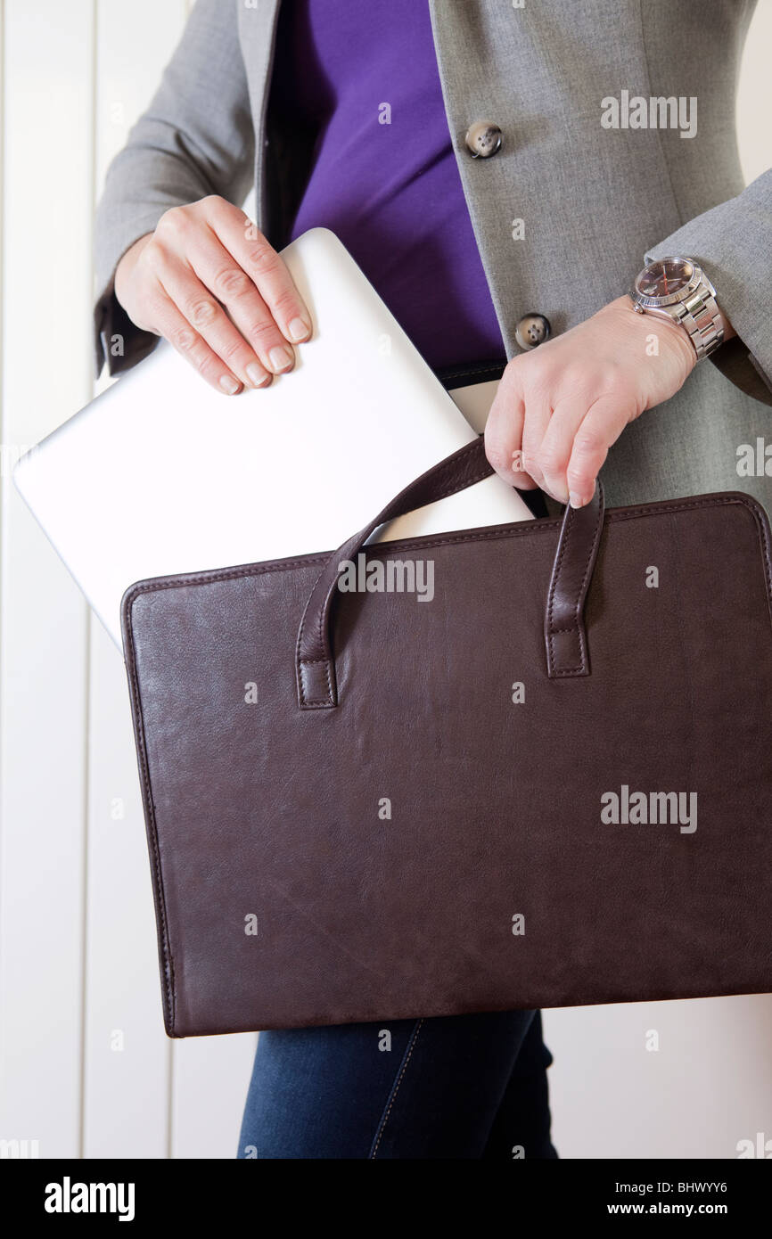 Businesswoman taking out laptop from her bag Stock Photo