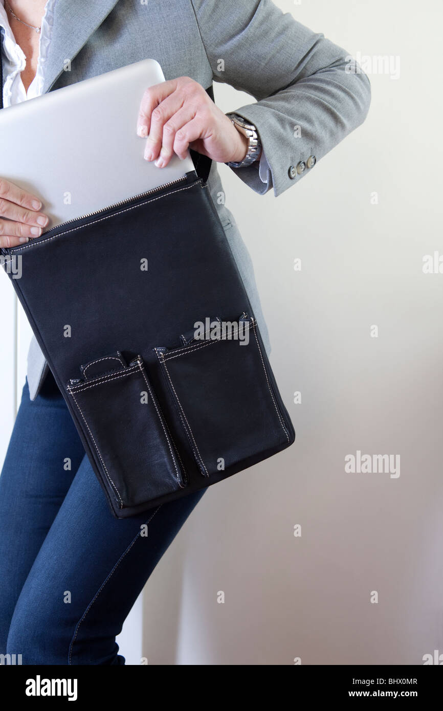 Woman extracting apple mac laptop from casual leather bag Stock Photo