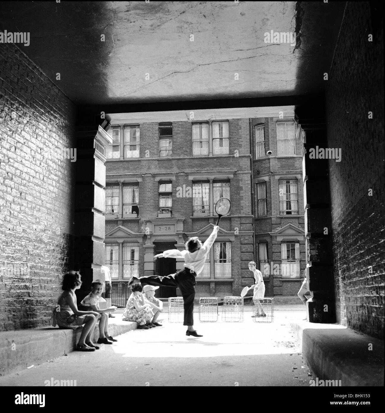 Inspired by the Wimbledon tennis championships taking place, these children enjoy a game of tennis in the back streets around Stock Photo