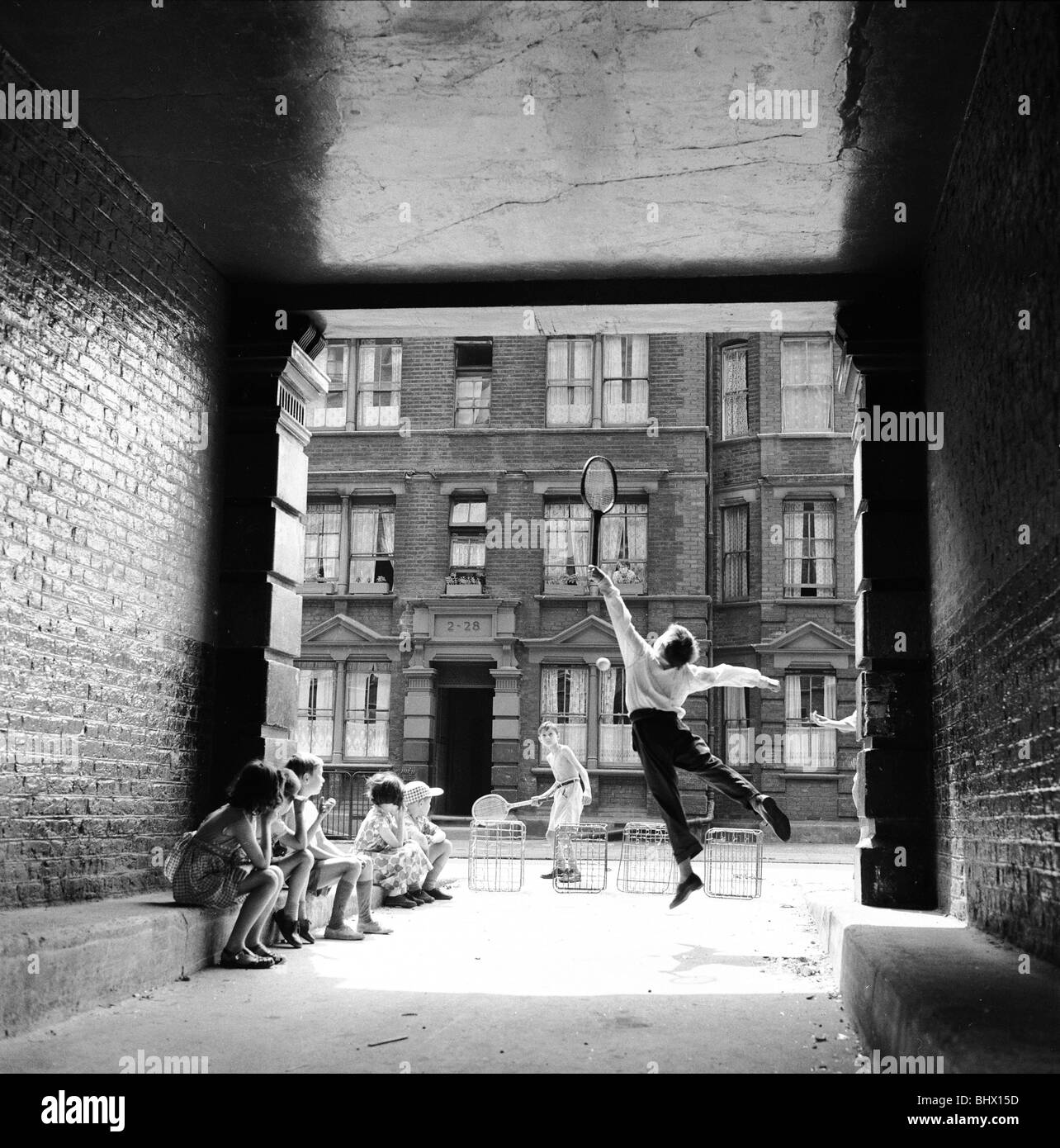 Inspired by the Wimbledon tennis championships taking place, these children enjoy a game of tennis in the back streets around their home in South East London. 9th July 1961. Stock Photo