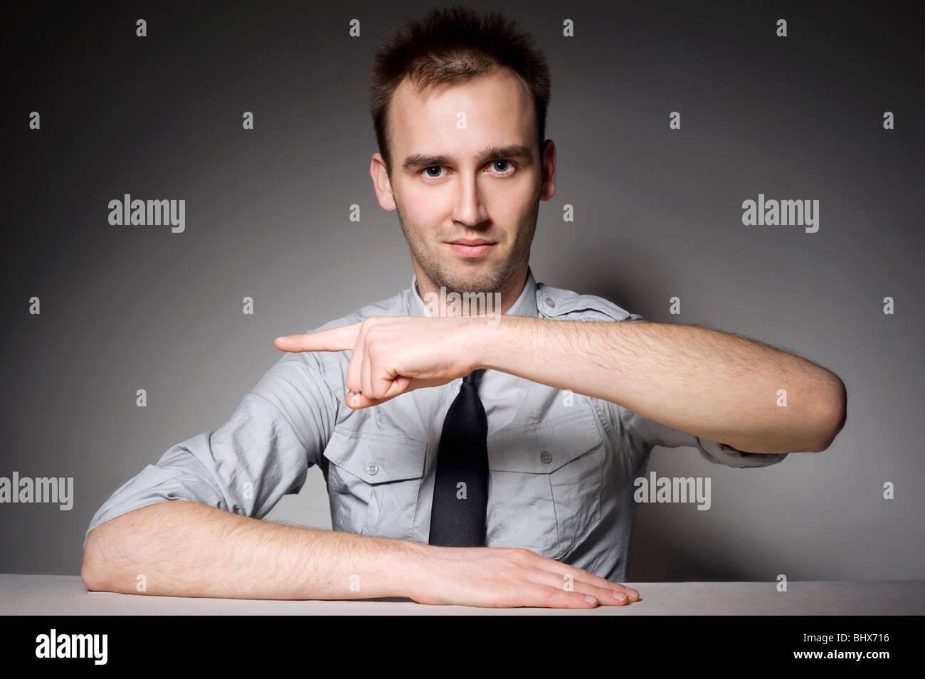 portrait of man sitting behind the table and pointing toward copy space Stock Photo