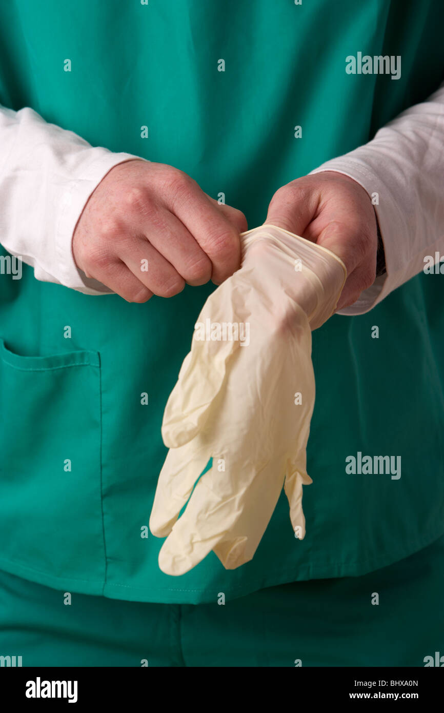 man wearing medical scrubs putting on a of rubber gloves Stock Photo