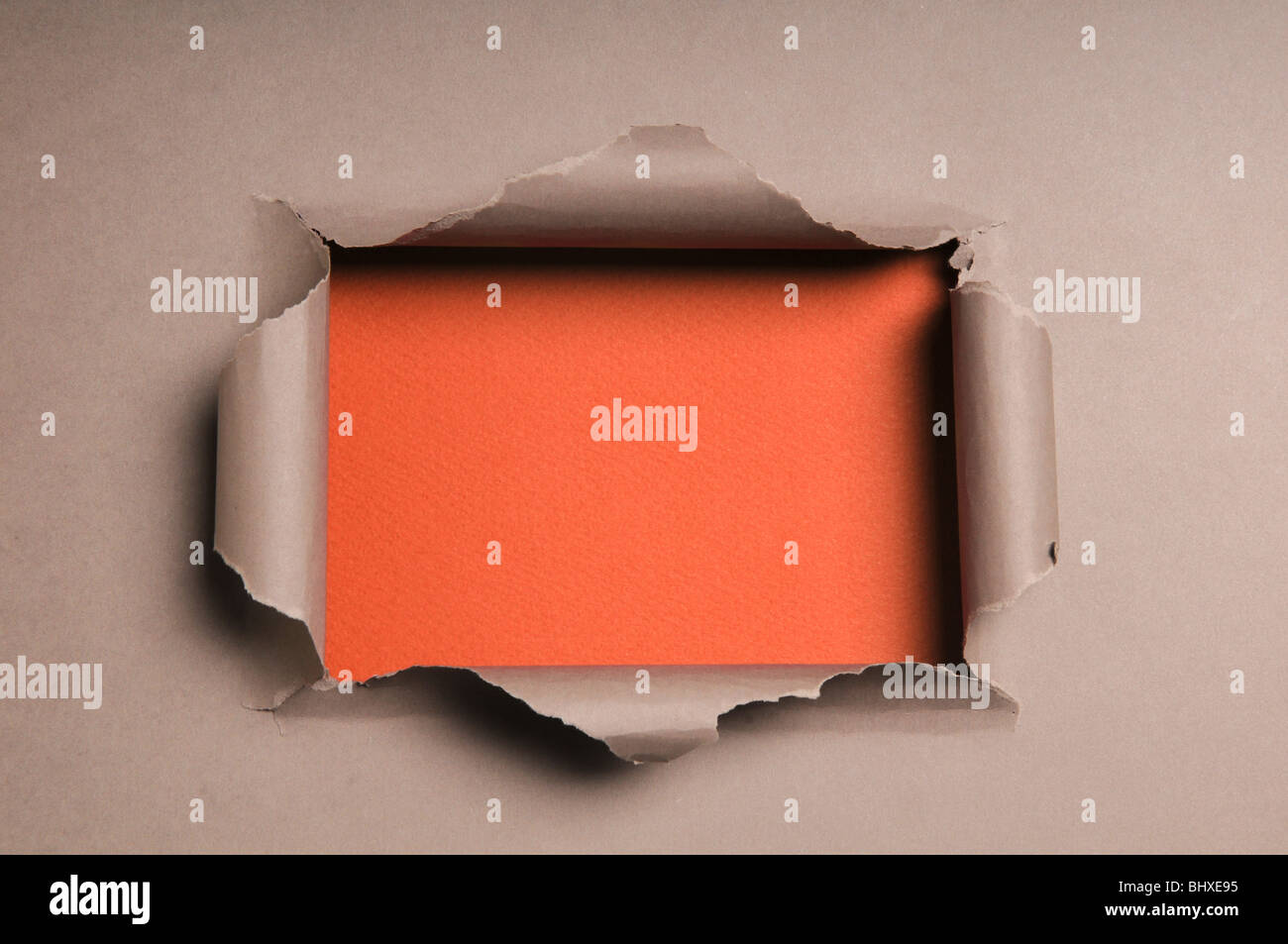 Beige paper ripped to form a rectangle over orange paper in background Stock Photo