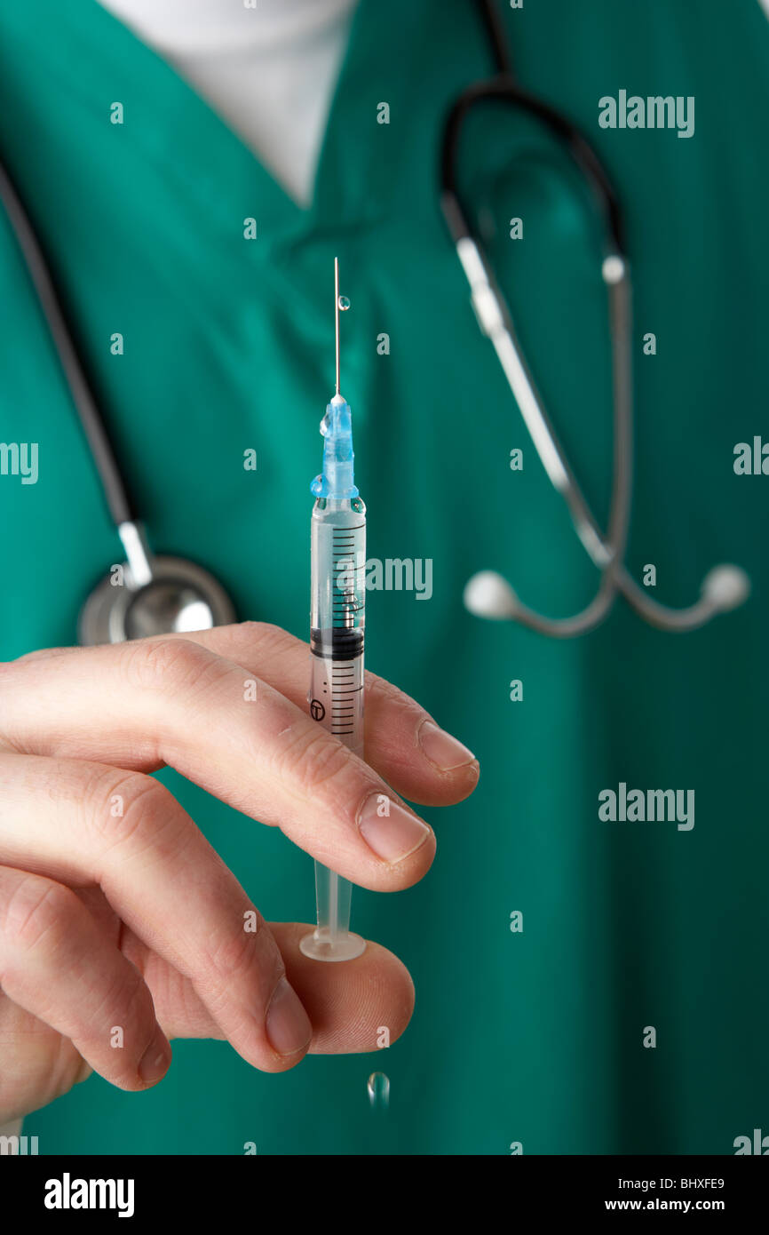 man wearing medical scrubs and stethoscope holding needle and syringe containing liquid Stock Photo