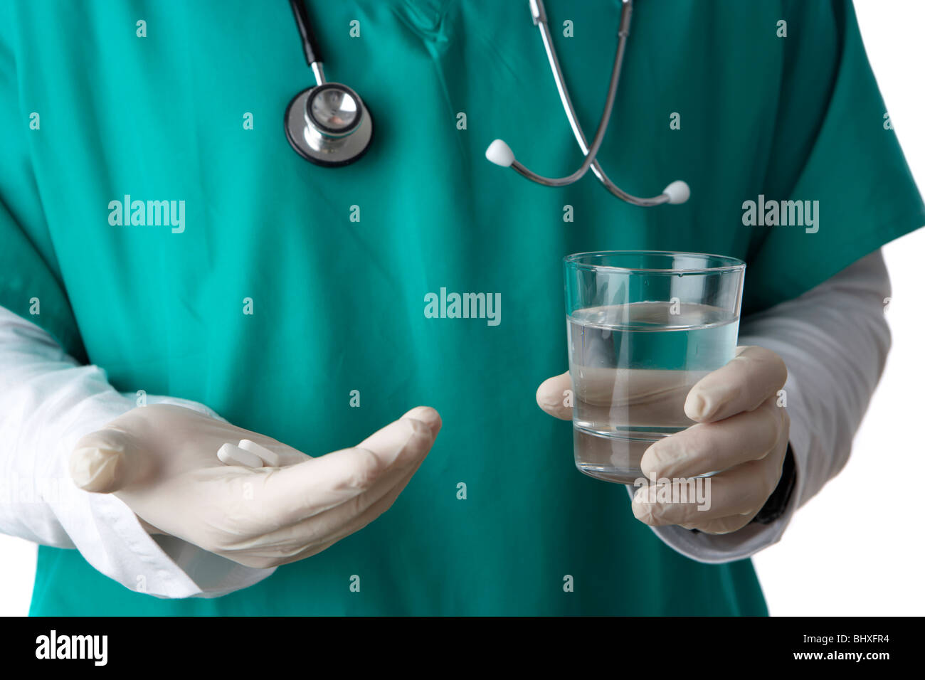 man wearing medical scrubs and stethoscope holding glass of water and pills Stock Photo