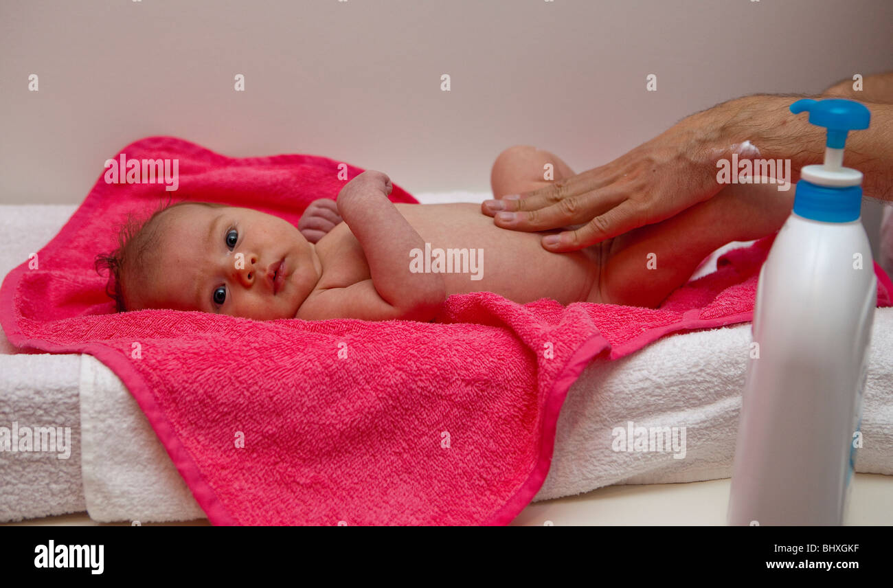 Baby girl being towelled dry and moisturised after a bath Stock Photo