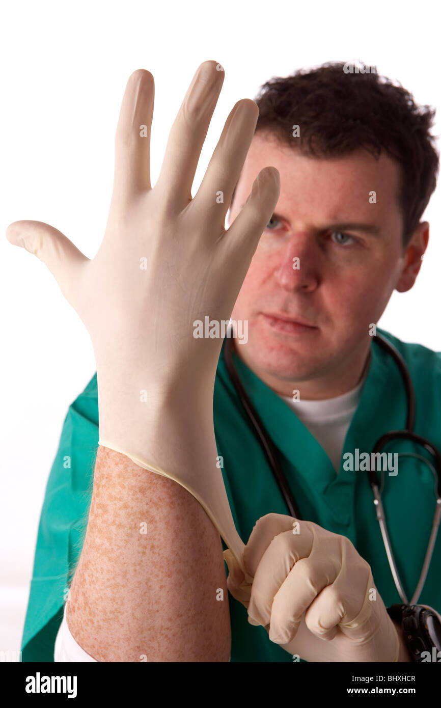 man wearing medical scrubs and stethoscope putting on a pair of rubber gloves Stock Photo