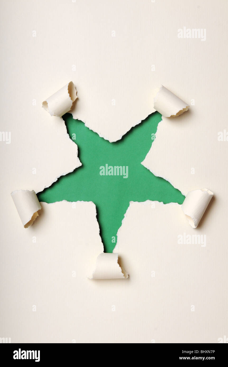 Old discolored paper ripped to form star over green background Stock Photo