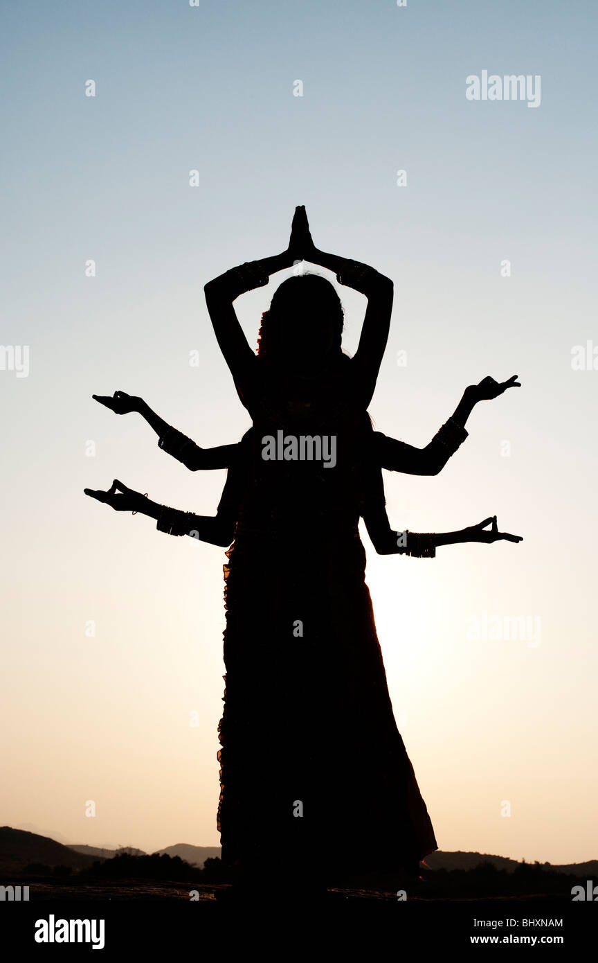 Silhouette of three indian girls in a classical six armed hindu goddess pose at sunset. India Stock Photo