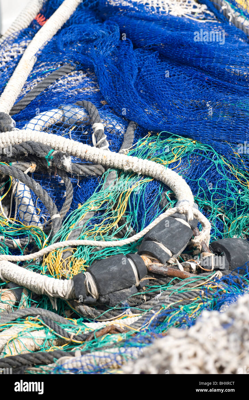 Multi-colored fishing nets raises the crane on the pier by the sea. Fish  production. Repair of networks Stock Photo - Alamy