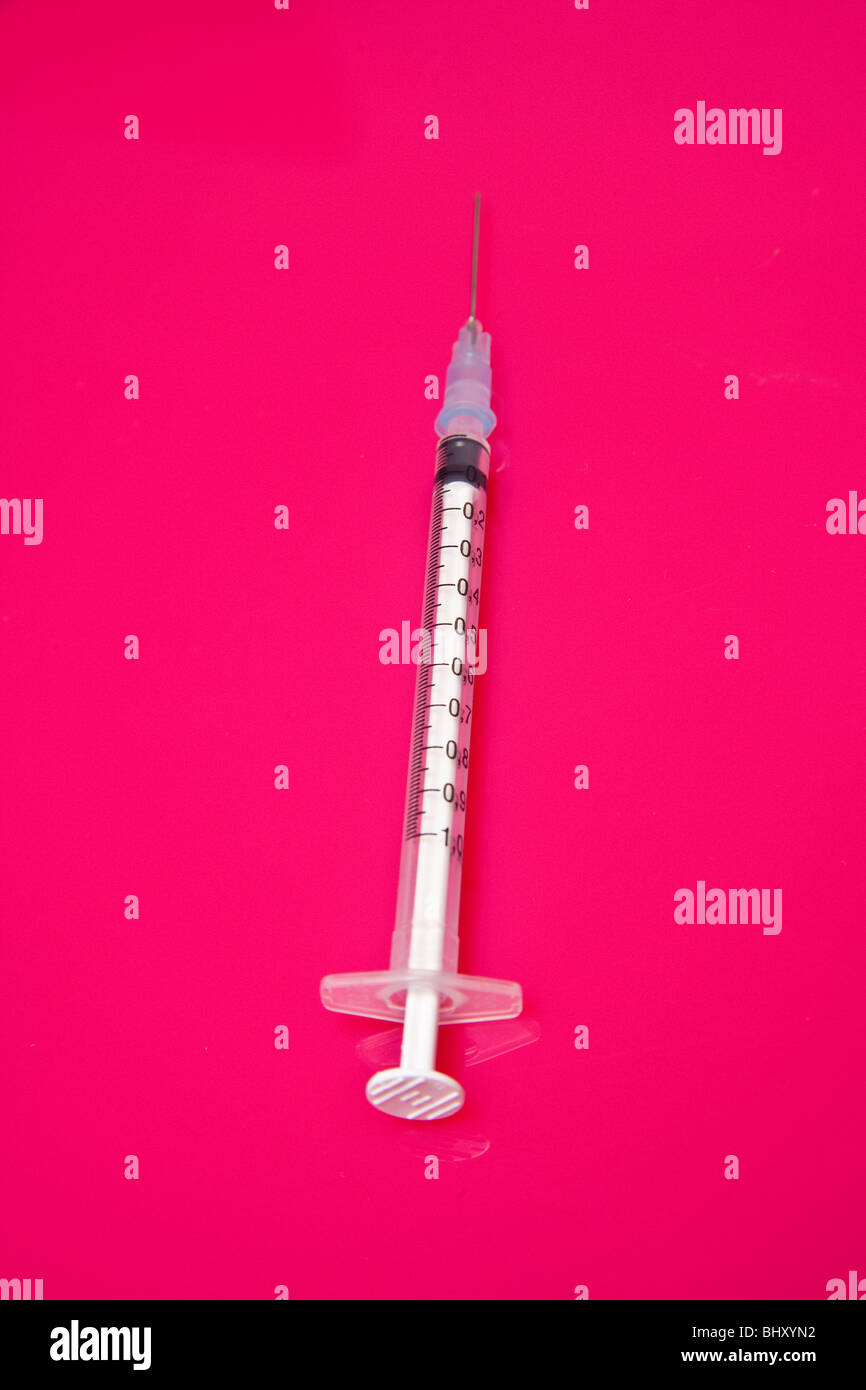 Needle and syringe on a bright pink studio background. Stock Photo