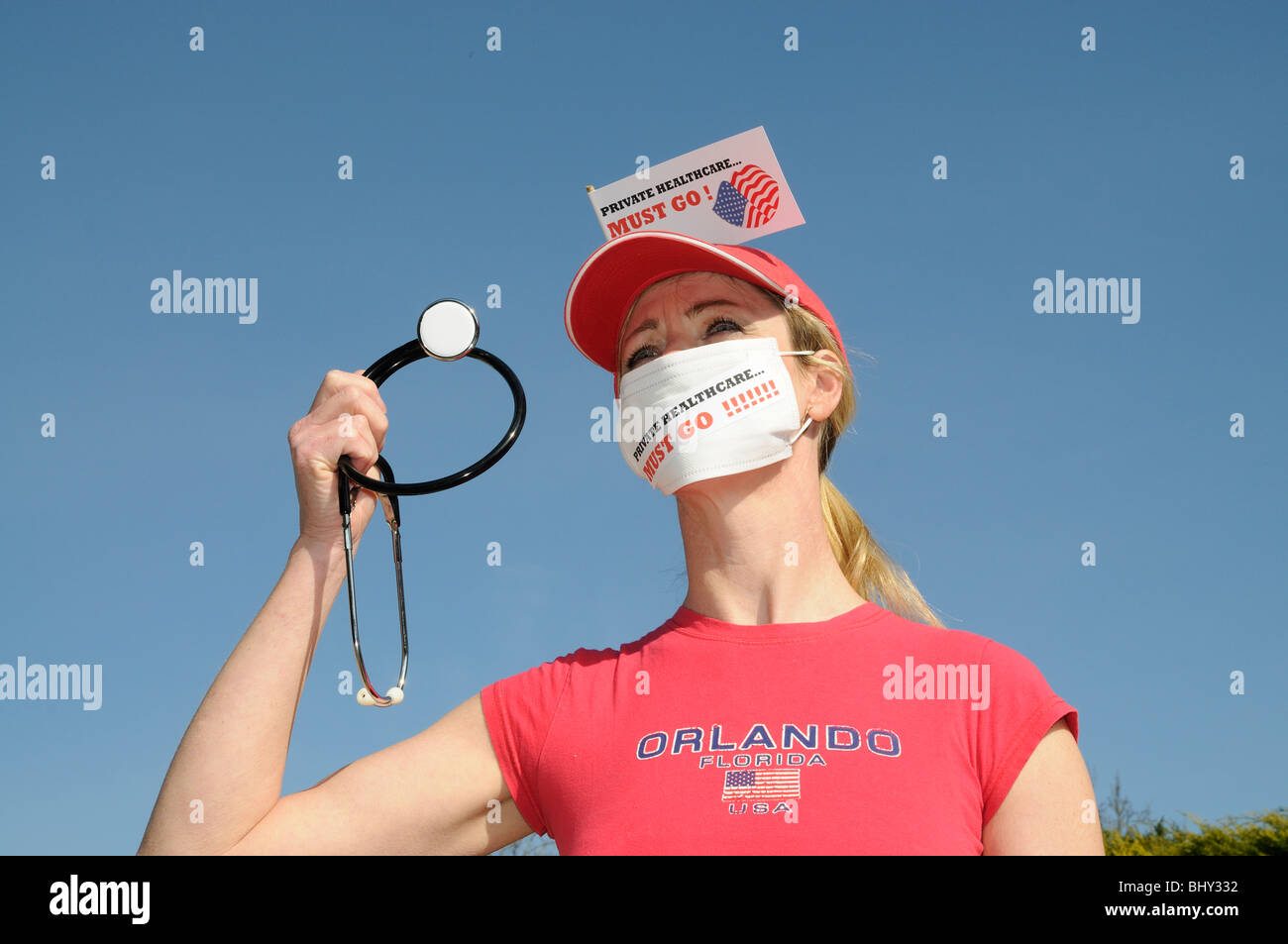 Private healthcare in the USA must go female protester wearing a medical face mask and holding a stethoscope Stock Photo