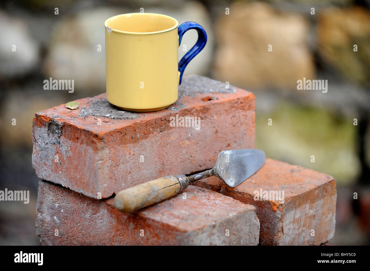 A builders mug of tea on a stack of reclaimed red bricks UK Stock Photo