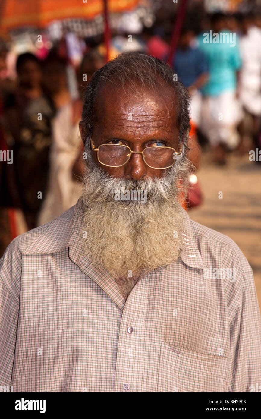 India, Kerala, Alappuzha, (Alleppey) Arthunkal, bearded man looking over glasses with untreated cataract in left eye Stock Photo