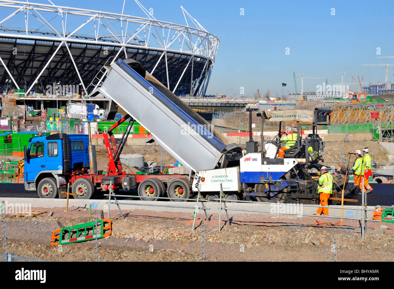 Close up of tipper lorry truck tipping tarmac into road laying machine new road at 2012 Olympic Stadium building construction site Stratford London UK Stock Photo