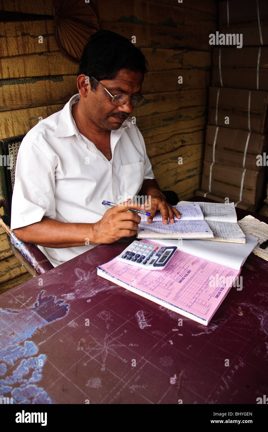A shop keeper doing the paperwork. Kollam, Kerala, India. Stock Photo