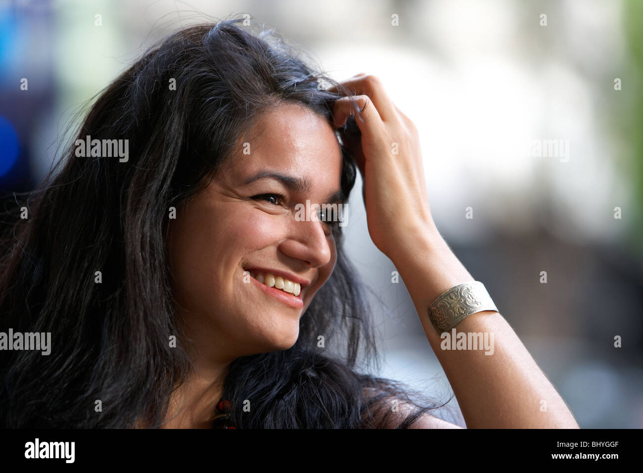 mid twenties hispanic woman running her fingers through her hair outside flirting Stock Photo