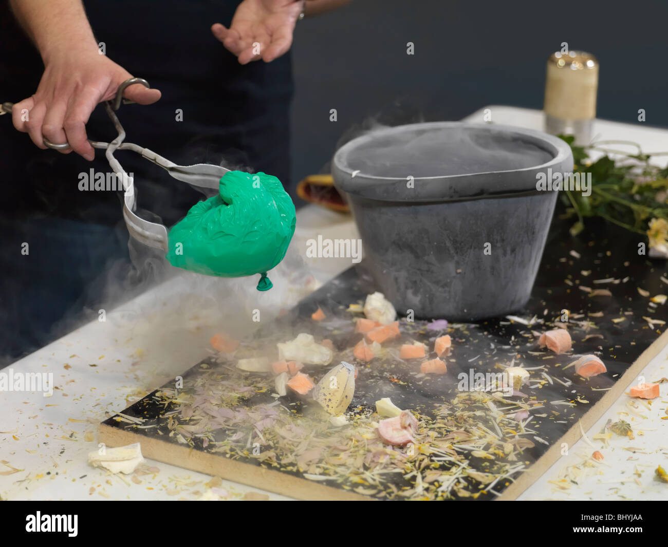 Person taking a shrunk air balloon out of a container with liquid nitrogen Stock Photo