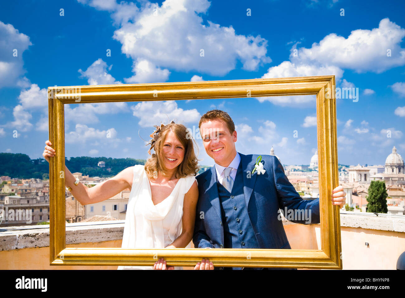 Bride and groom holding gold picture frame on wedding day in Rome, Italy Stock Photo