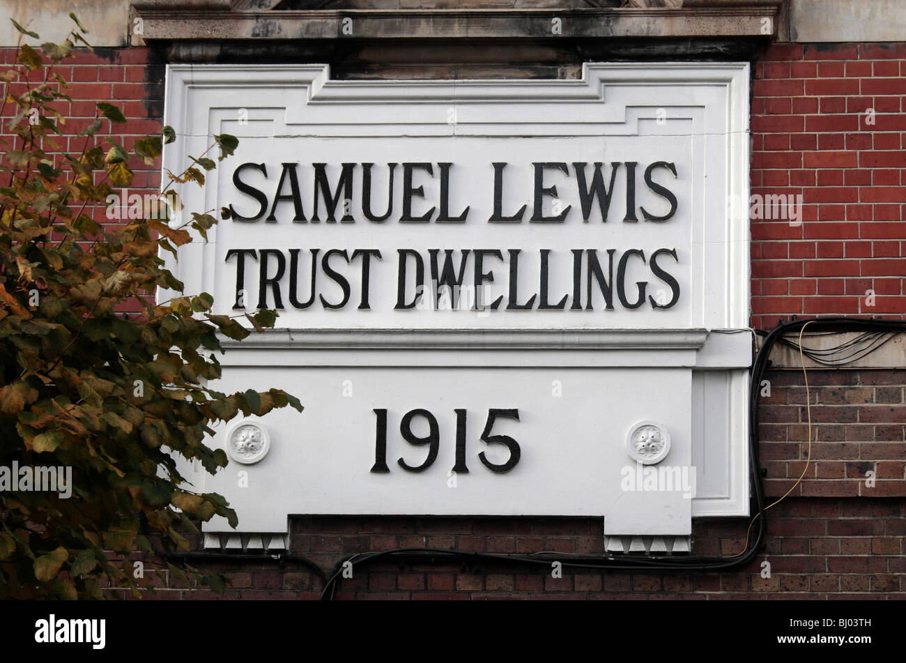 The Samuel Lewis Trust Dwellings sign on the side of a block, Ixworth Place, London, UK. Stock Photo