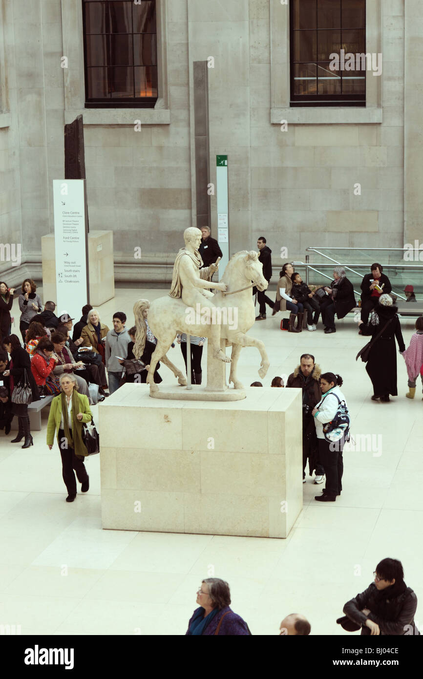 The British Museum visitors and tourists view a Roman marble sculpture of a young man on horseback in the Great Court Stock Photo