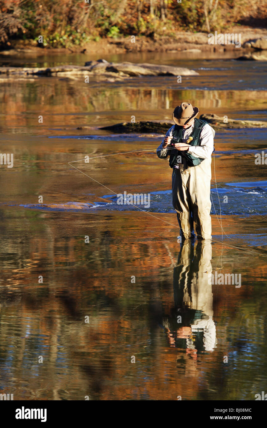 Man wearing a cowboy hat while fly fishing in a river in the