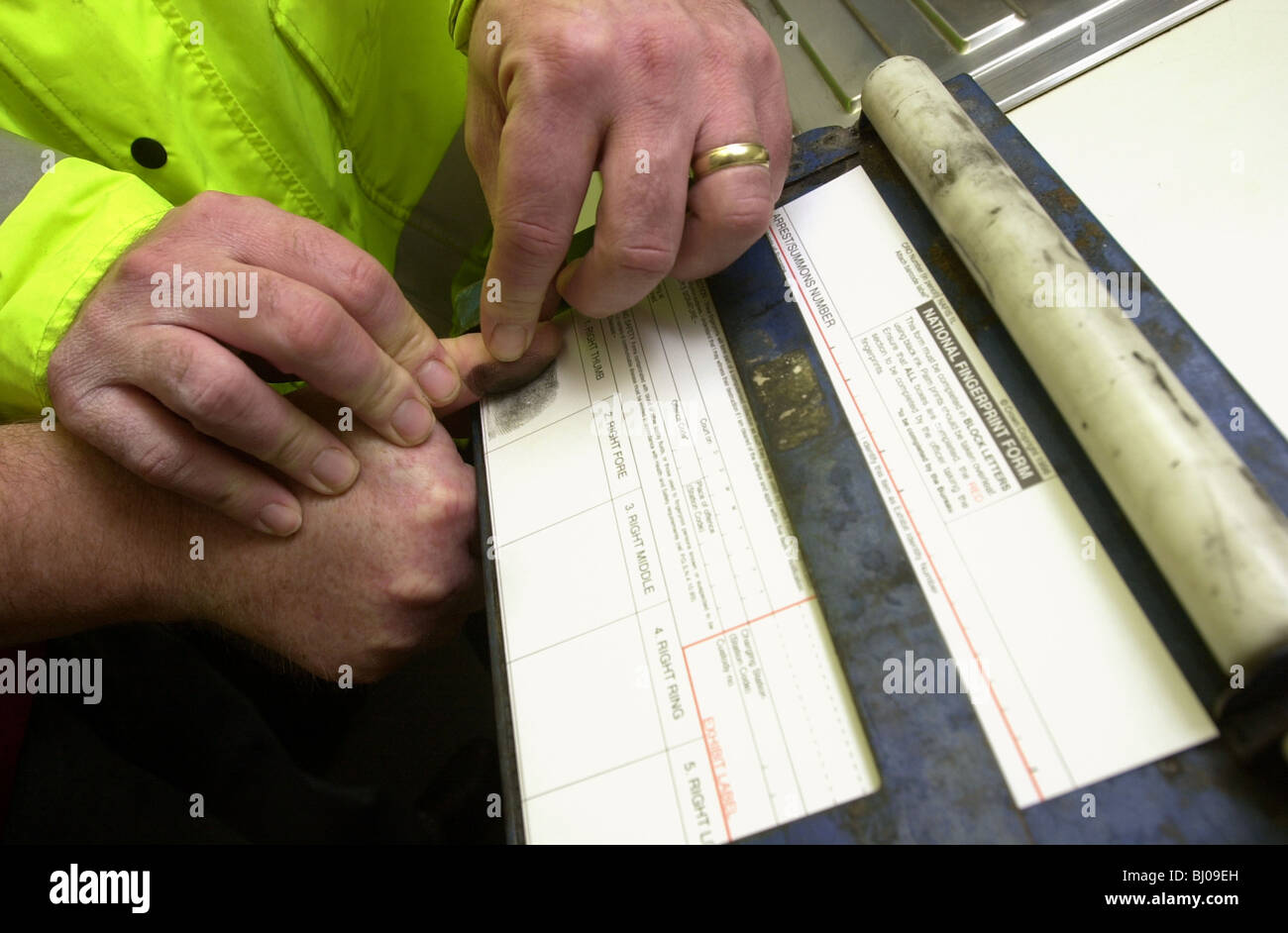 Police officer takes the imprint of a mans right thumb using a traditional ink methid finger prints UK Stock Photo