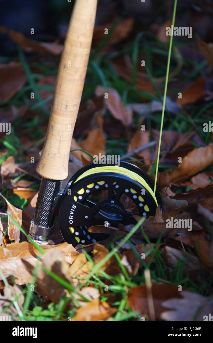 CLOSEUP VIEW ORVIS FLY FISHING ROD REEL SITTING ON LEAVES AT FEET OF FISHERMAN Stock Photo