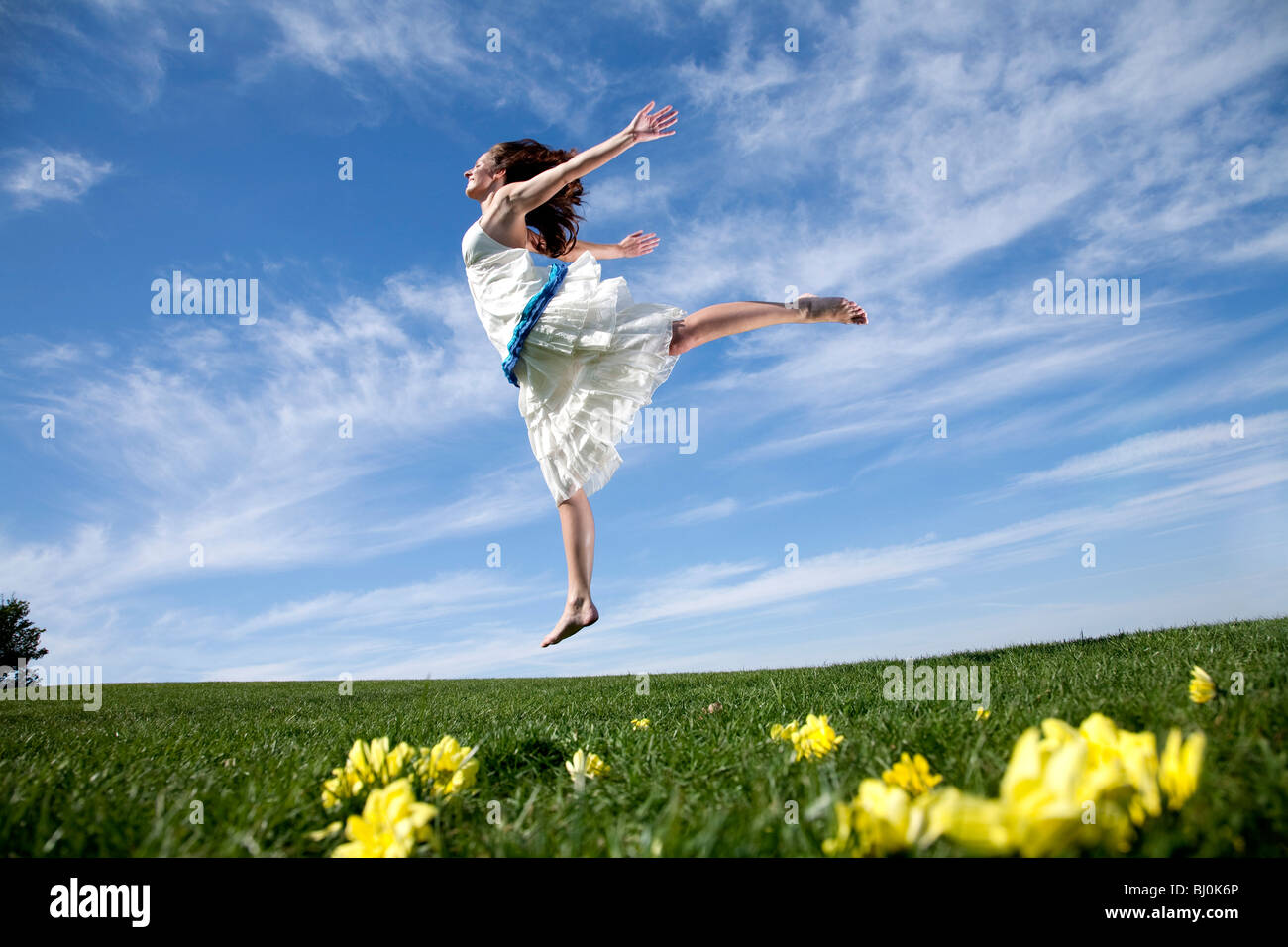 young woman in park jumping on lawn Stock Photo