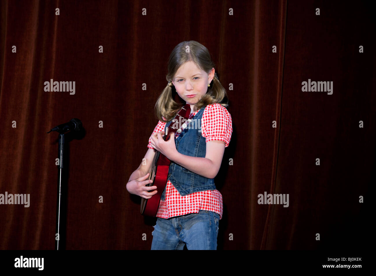 young girl playing guitar on stage Stock Photo