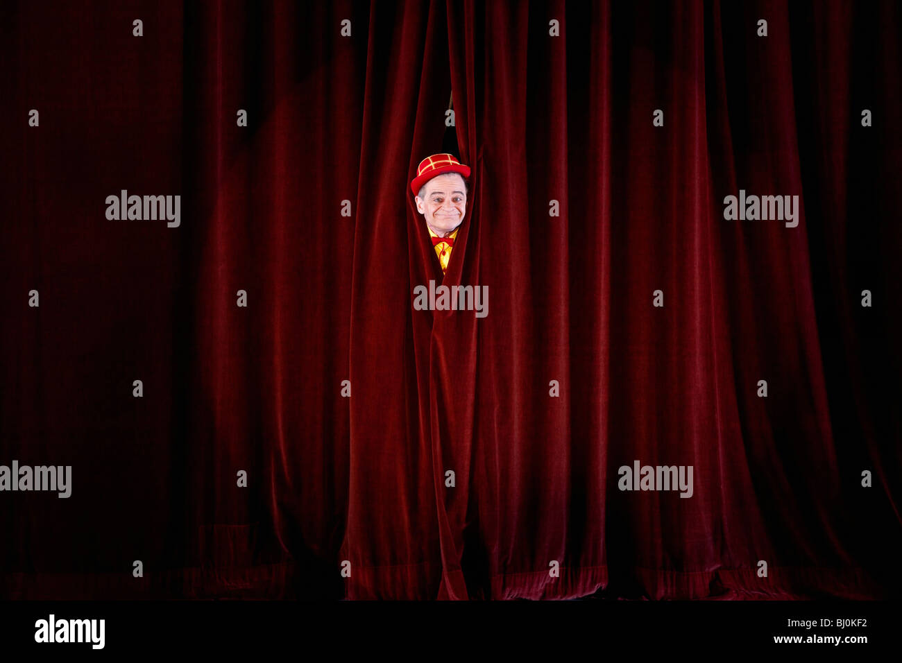 clown on stage peeking through curtain Stock Photo