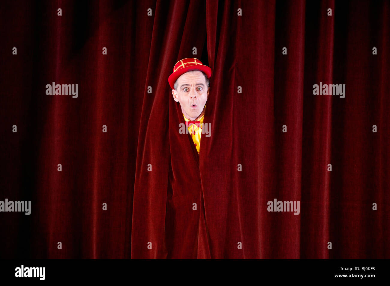 clown on stage peeking through curtain Stock Photo